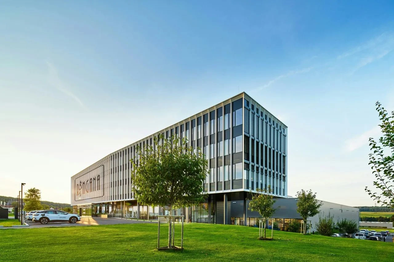 AI-generated visualization of a modern RINGANA building with a green lawn and trees