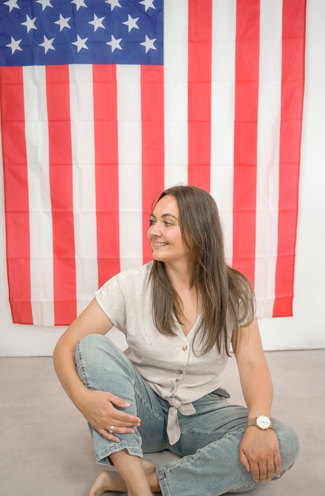 Tanja Klingberg sitting on the floor in front of an American flag, smiling
